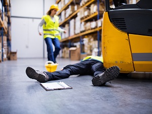 A warehouse worker is on the ground because they were struck-by a forklift.