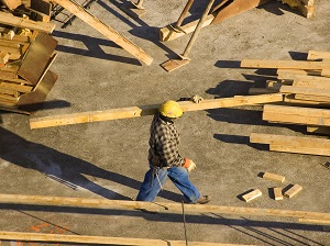 Construction worker carrying lumber on a job site.