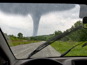 A view of a tornado in the distance as seen from someone sitting in a vehicle.