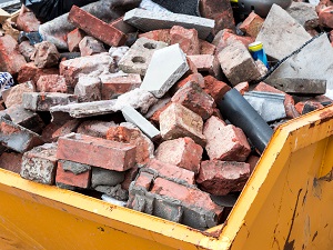 A large metal box holding bricks and demolition debris.