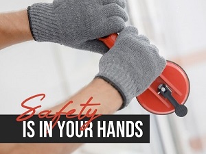 A window worker lifiting a piece of glasswith a special tool and the phrase, "Safety is in your Hands."