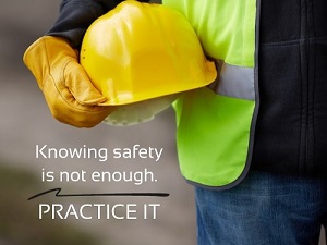 A construction worker holding a hard hat with the phrase, "Knowing Safety is Not Enough, Practice It."