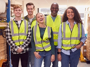 Five co-workers smiling and wearing safety vests.