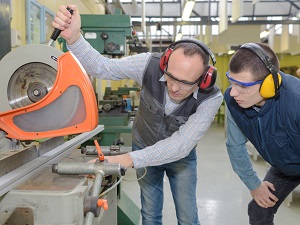 Supervisor showing a younger employee how a tool works safely.