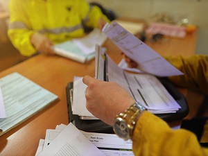 Two workers looking through papers on a desk as they compile research.