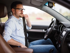 A man in a car buckling his seatbelt.