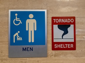 Tornado shelter sign outside of a Men's restroom.