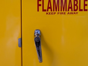 A yellow fire cabinet that says Flammable, Keep Fire Away.