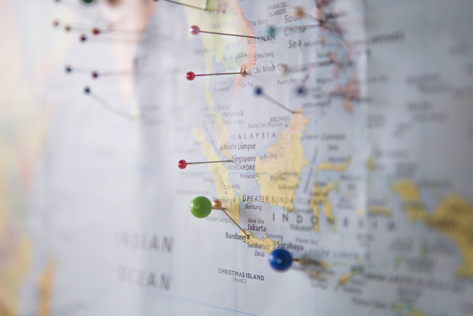 A dozen multi colored push pins inserted into various locations on a world map marking favorite cities or those visited by a loved one during prior trips