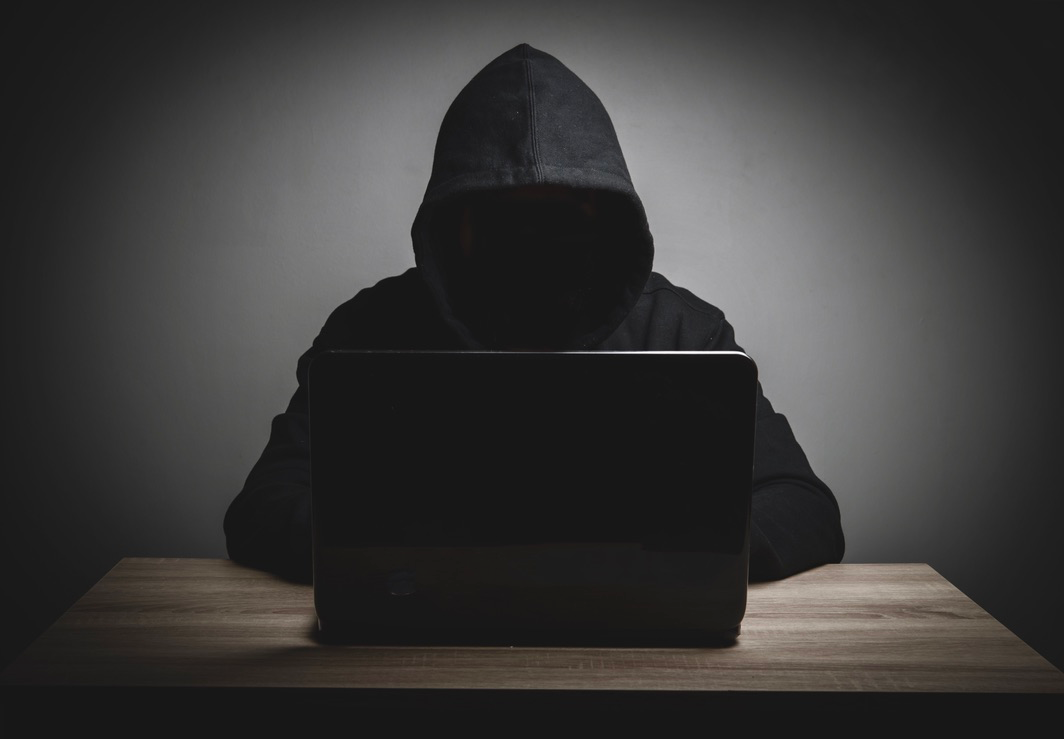 Hooded hacker accesses dark web with laptop