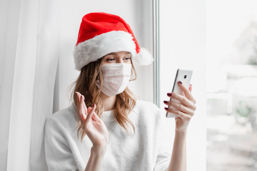 Young woman video chats loved ones wearing covid mask during holidays
