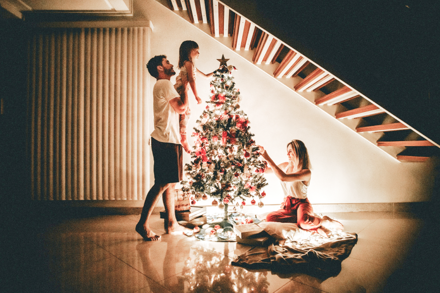 young family decorates christmas tree together