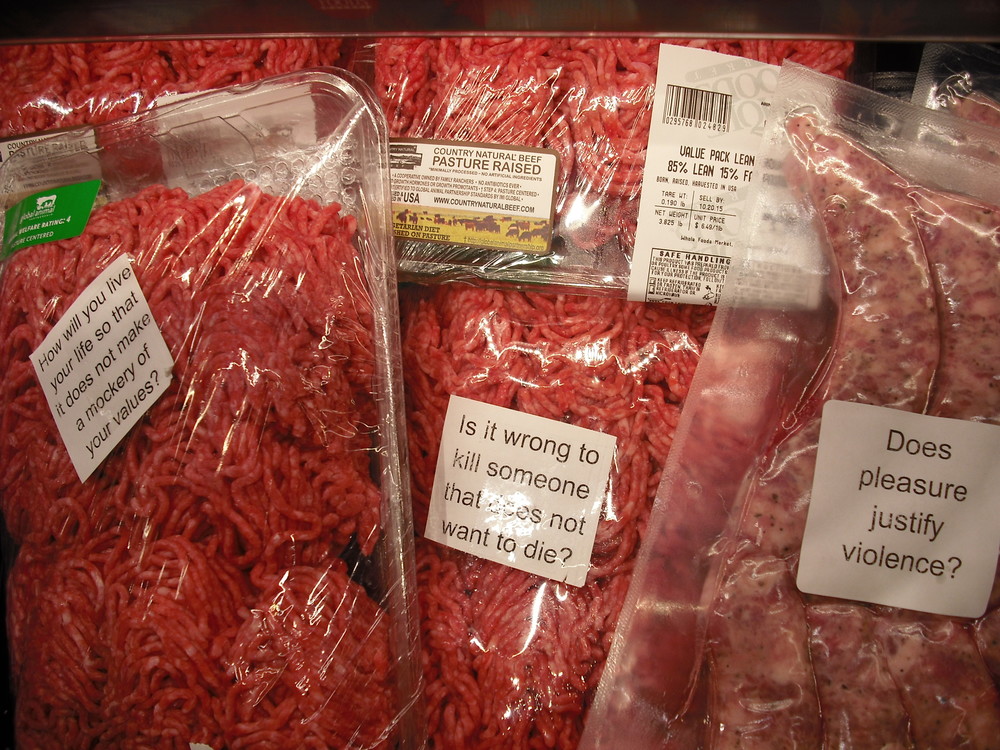 Packages containing animal flesh covered in stickers questioning the norms around eating animals' bodies.