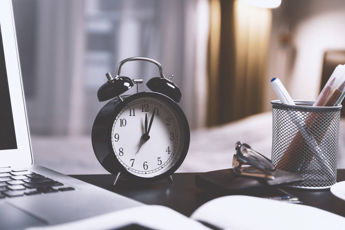 A black alarm clock on an office desk.