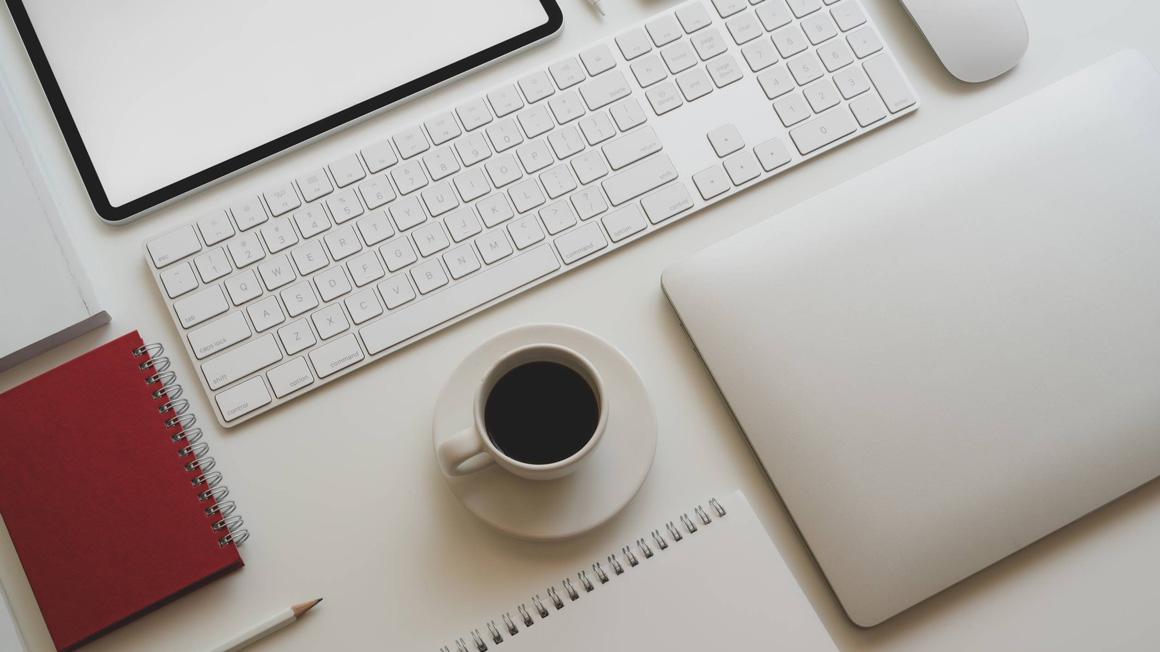 An organised white desk with equipment and accessories.