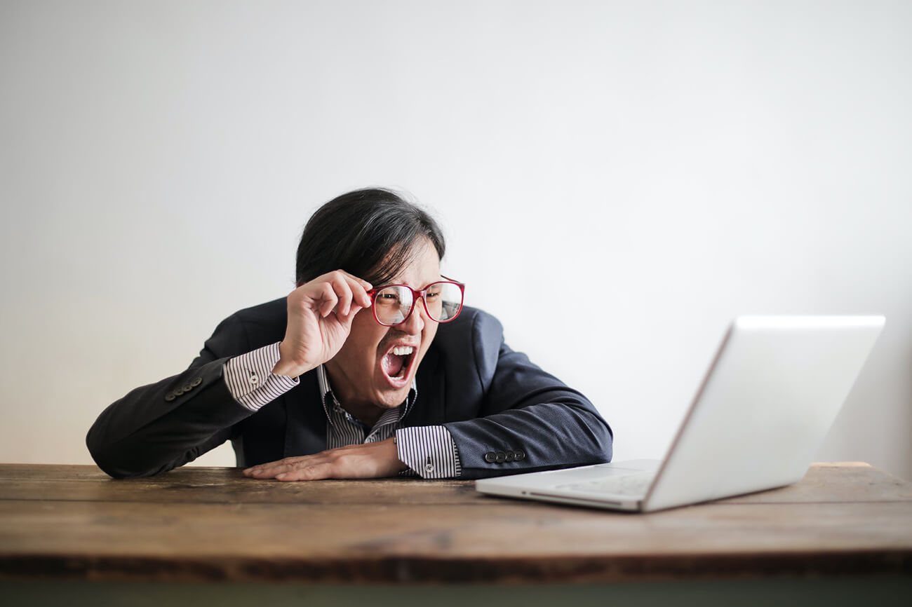 Stressed and angry employee screaming at laptop