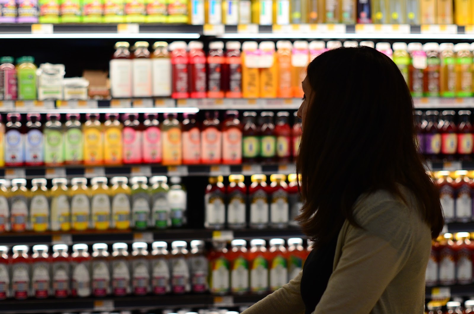 A person shopping in a grocery store with juice bottles in the background