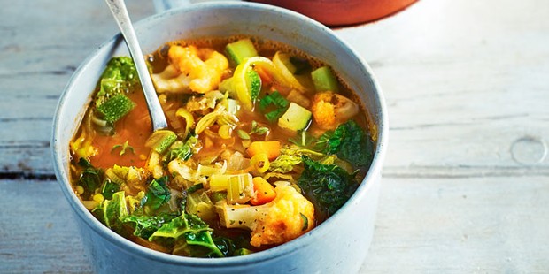 Rustic vegetable soup in a pot with a spoon