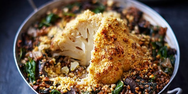 Whole roasted cauliflower in an oven dish with salad