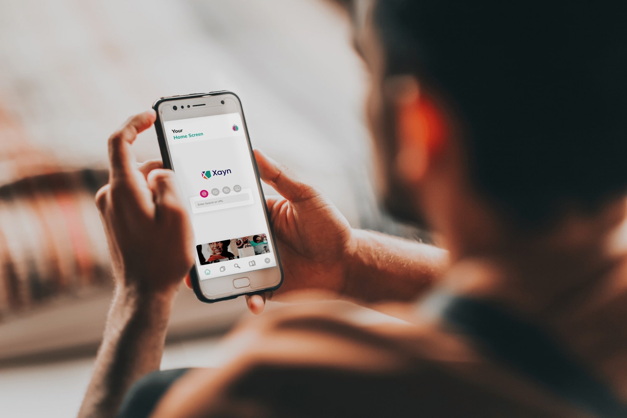 Xayn Mock man holding the phone with opened Xayn App on the Home screen