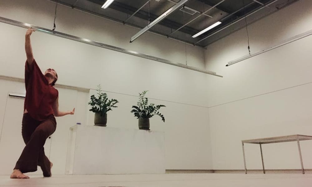 Anna Kempin captured performing at Atlas 2 contemporary dance project, standing and raising one hand high