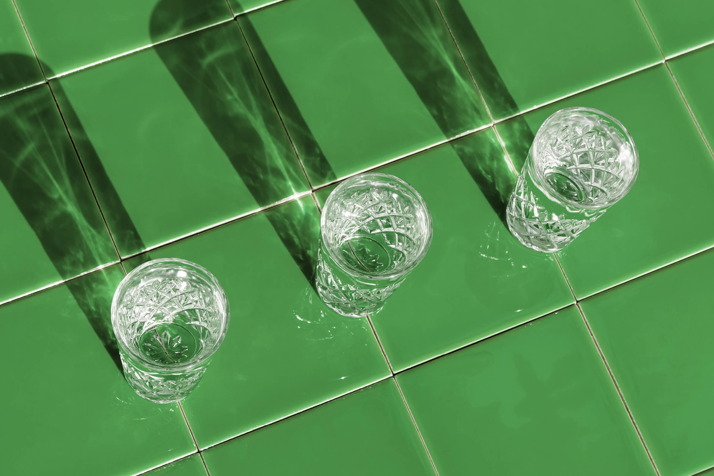 Longdrinkgläser auf grün gefliestem Hintergrund