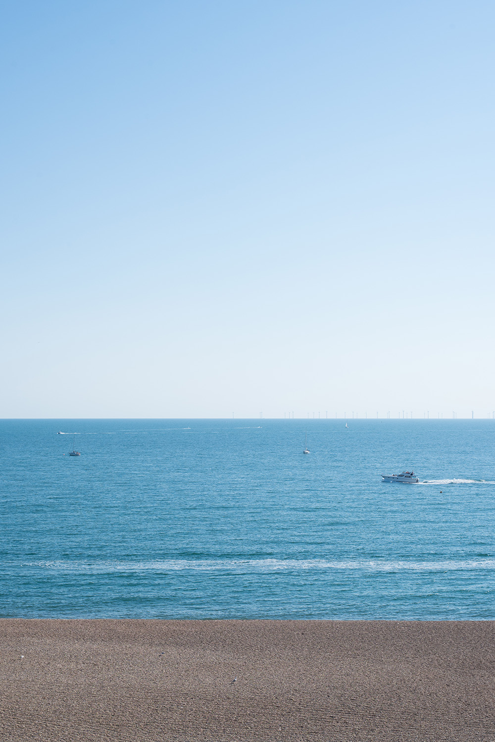 View out the sea on Brighton beach. It's a perfectly clear summers day with blue sea and cloudless light blue sky.
