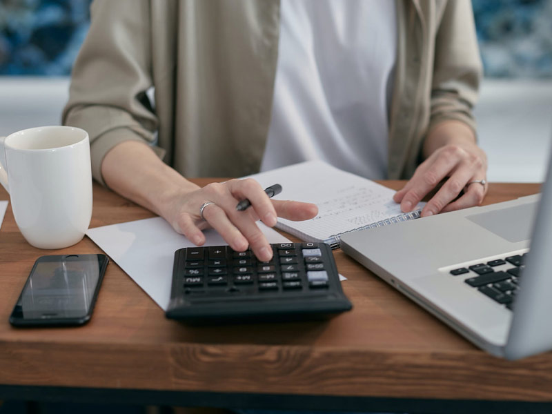 Woman working on a computer, using a calculator.