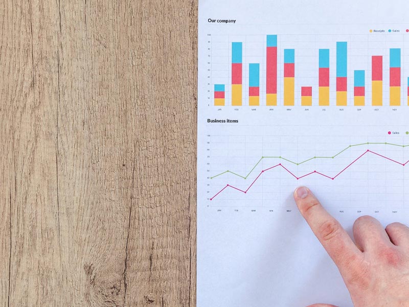 Someone pointing at a chart, on a table.