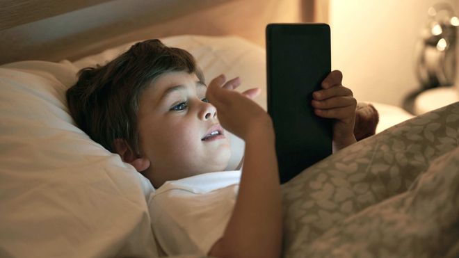 bé chơi ipad trên giường ngủ