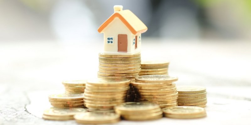 How to sell your house fast for market value - Yes Homebuyers. Image of a house on top of a stack of coins.