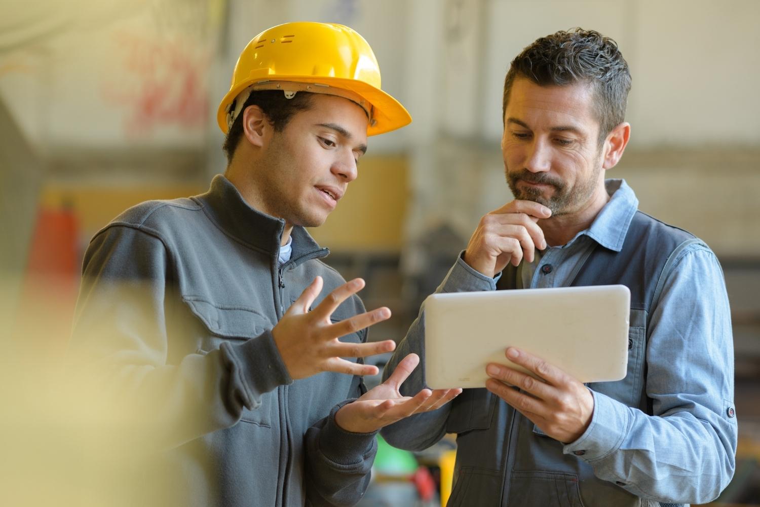 Two warehouse workers looking at a tablet for synchronized information due to software integration