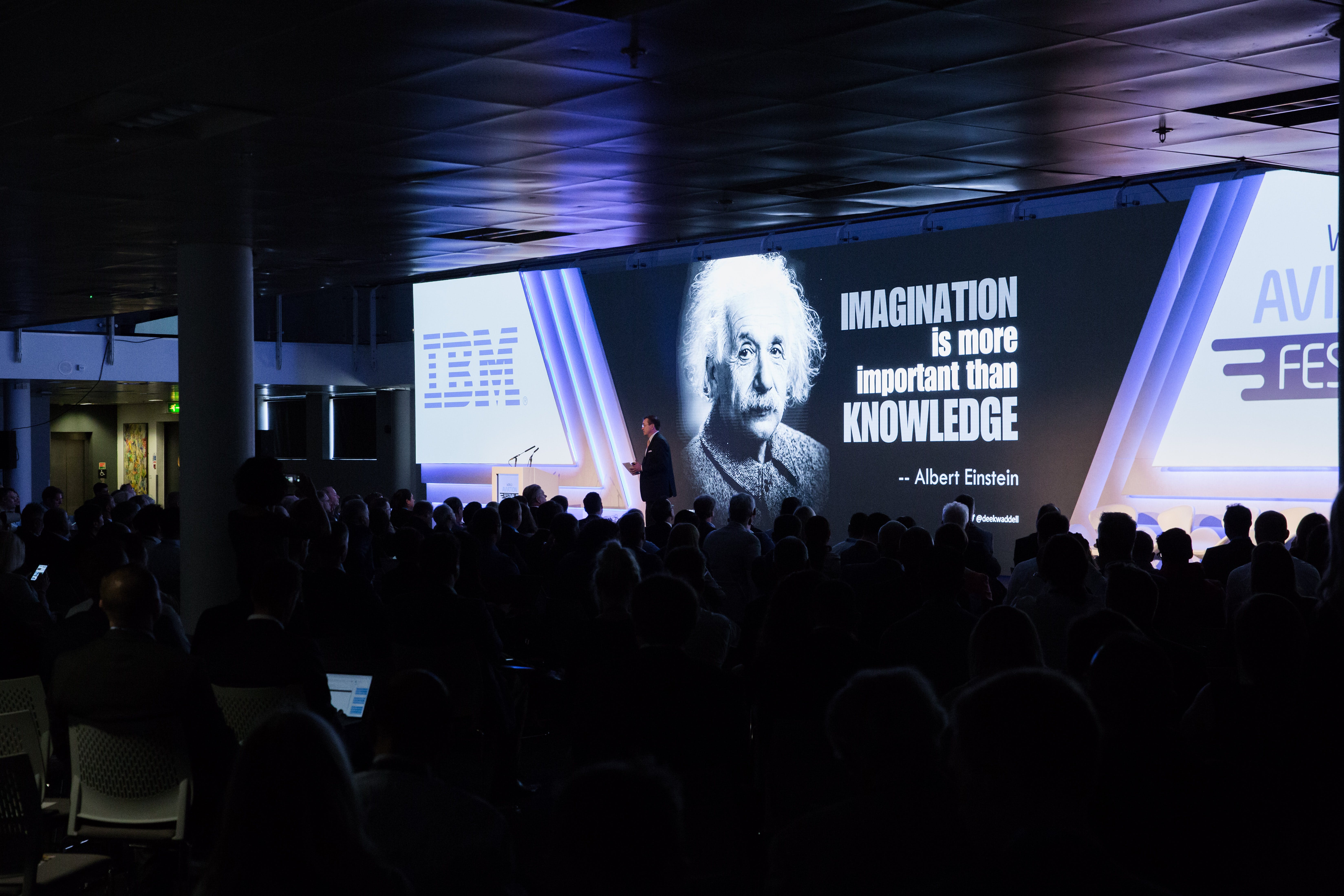 Presenter in front of Albert Einstein backdrop: Imagination is more important than knowledge