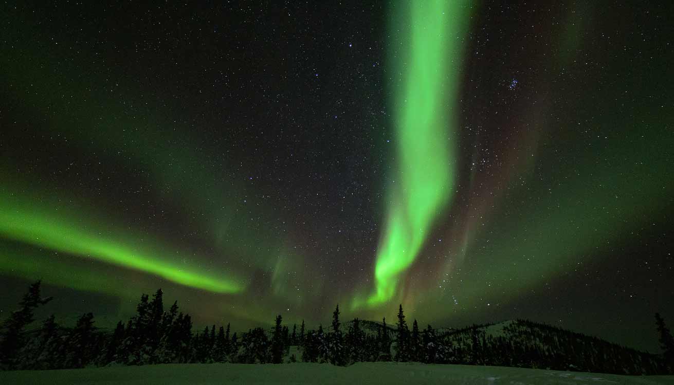 Green and pink northern lights at night in Alaska