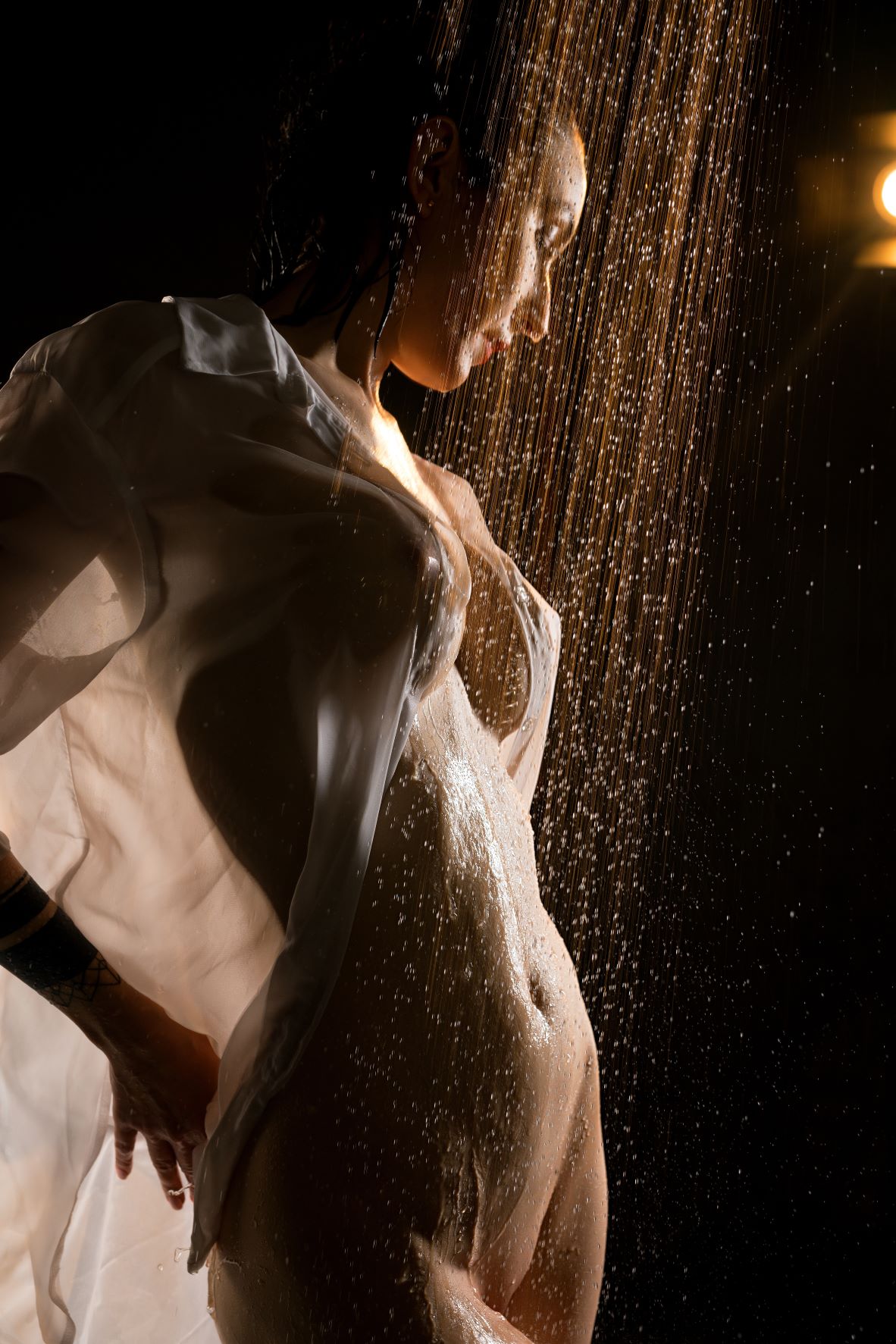 Woman in shower with wet shirt covering breasts