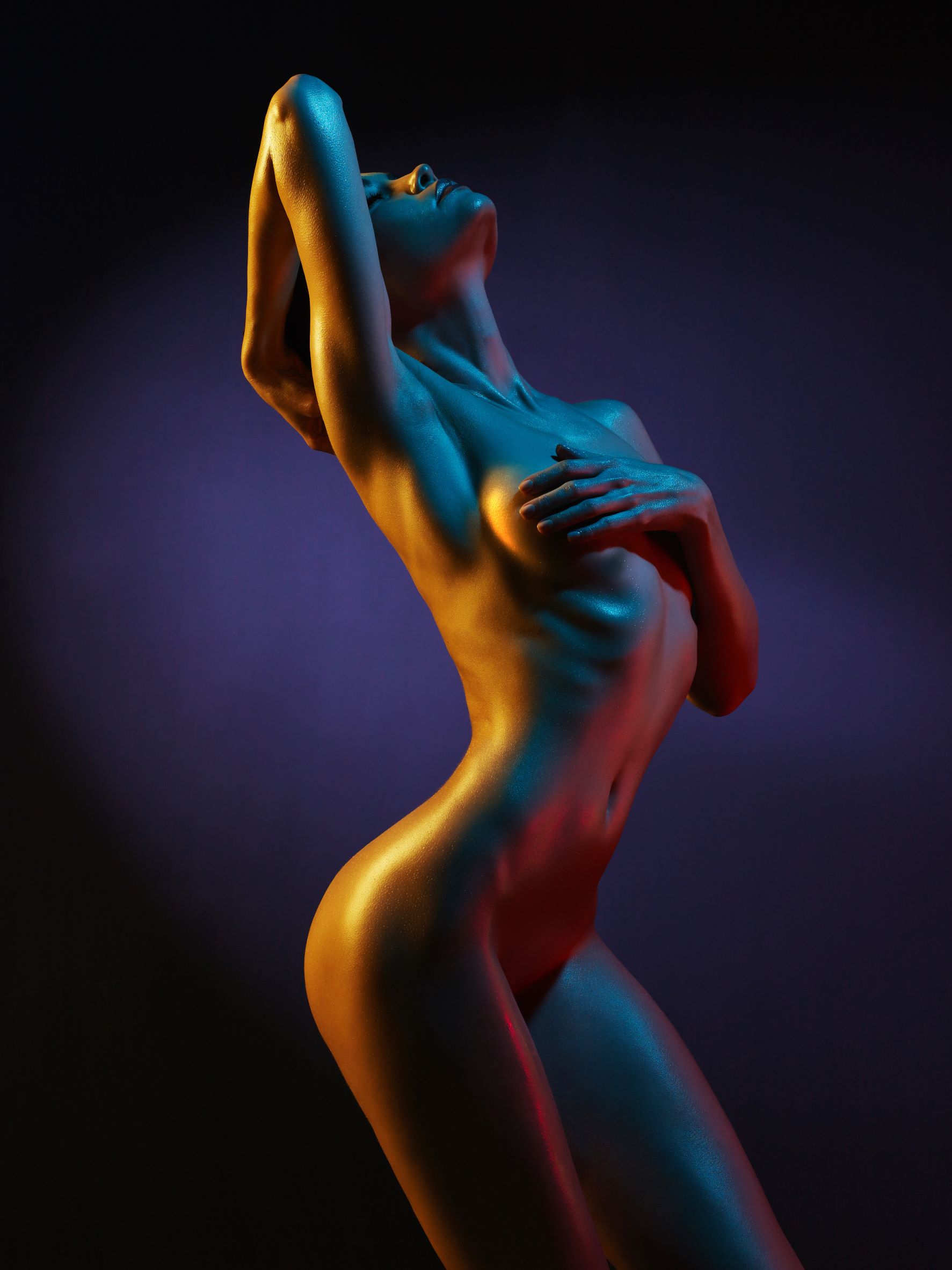 Nude woman leaning back covering breasts with hands