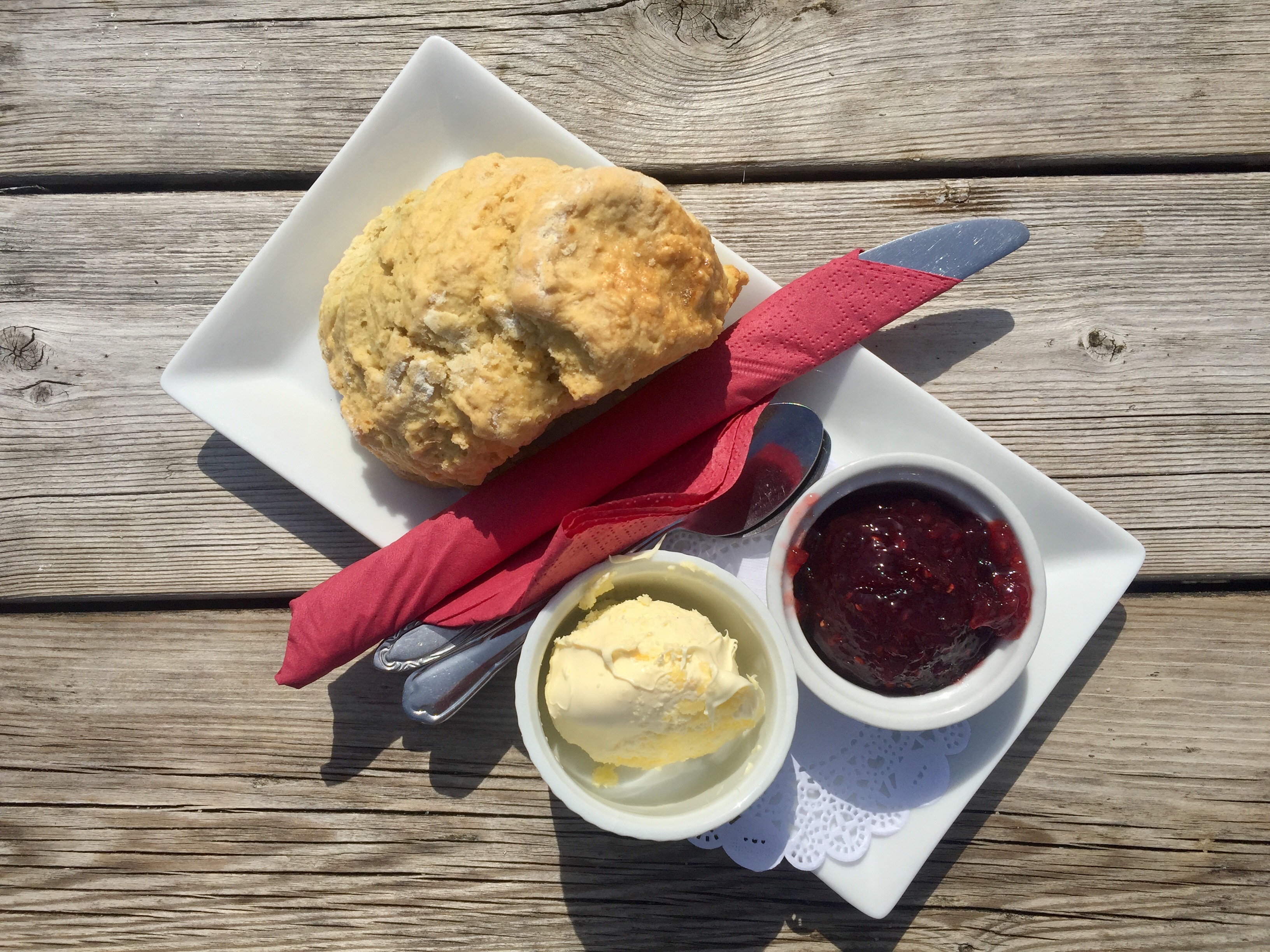 A delicious Cornish cream tea on a plate with a side of jam and butter