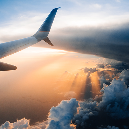 An airplane travels through the sky at sunset.