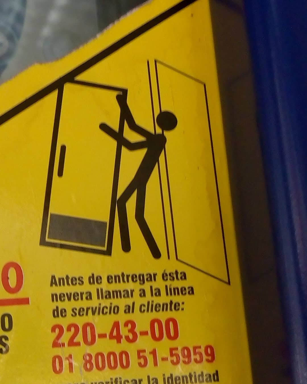 Ícono de advertencia de persona cargando un refrigerador. Parece que este último estuviera abalanceándose contra la persona.