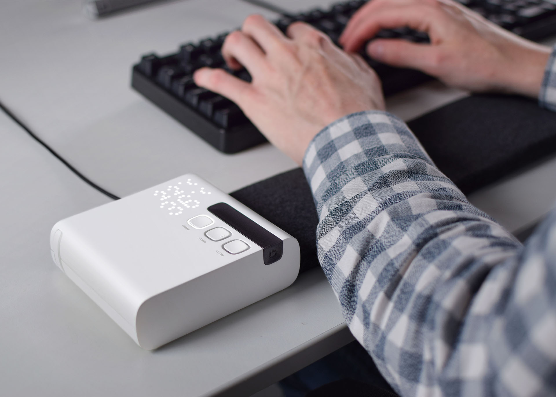 The Stratum heating and cooling mat being used at a desk, with the users wrists resting on the mat while typing
