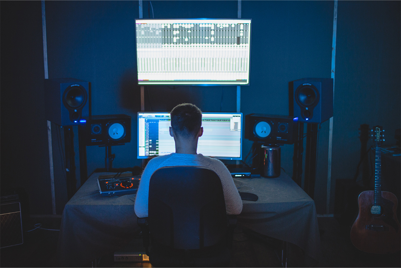 Music producer editing on two monitors in the dark