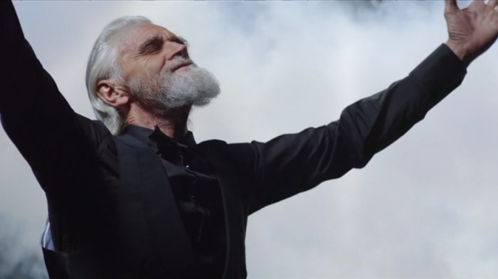 Buchanan commercial still of old magician with arms wide open