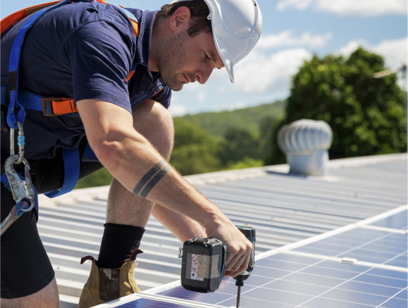 A solar installer installing panels onto a roof