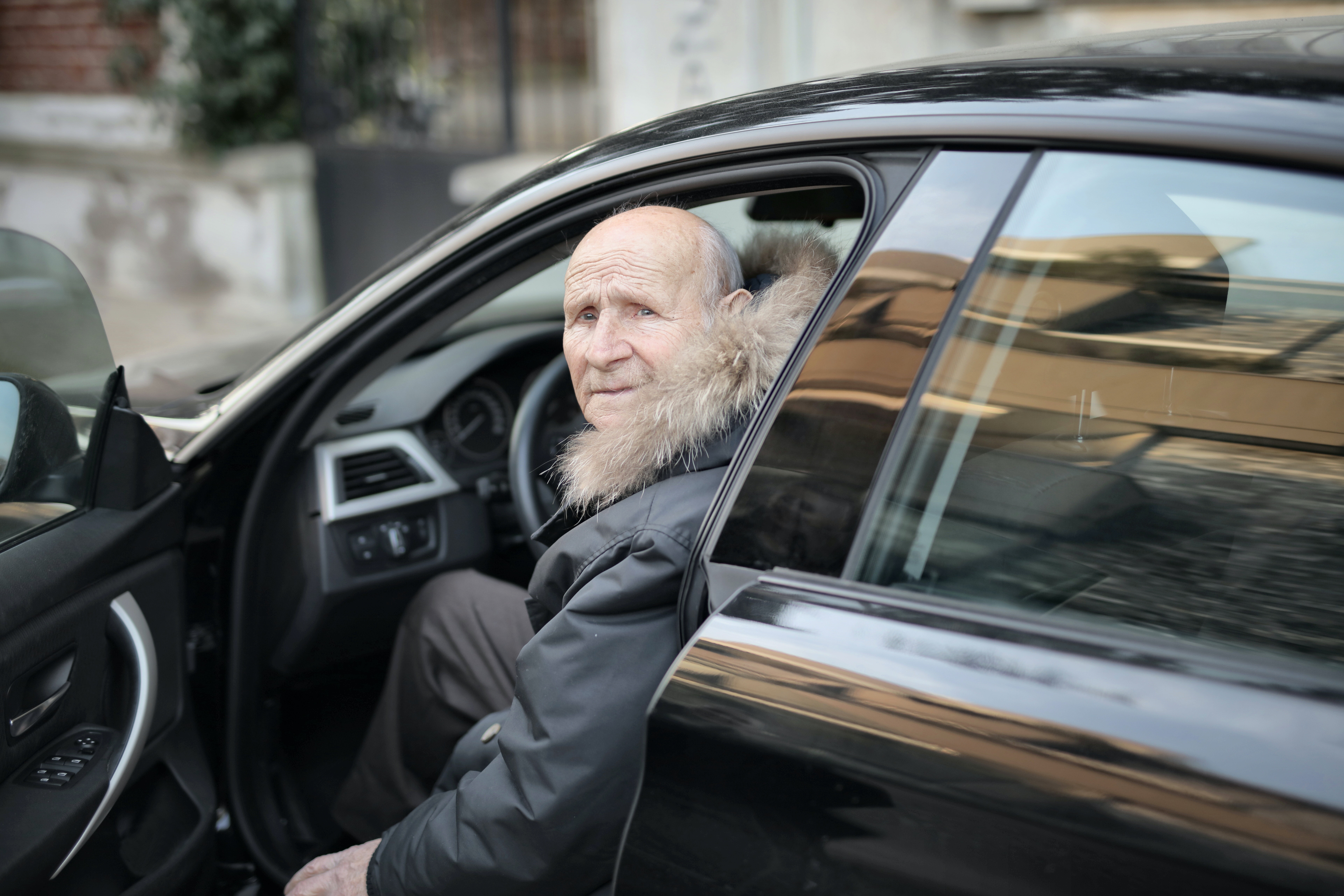 old man driving a black car