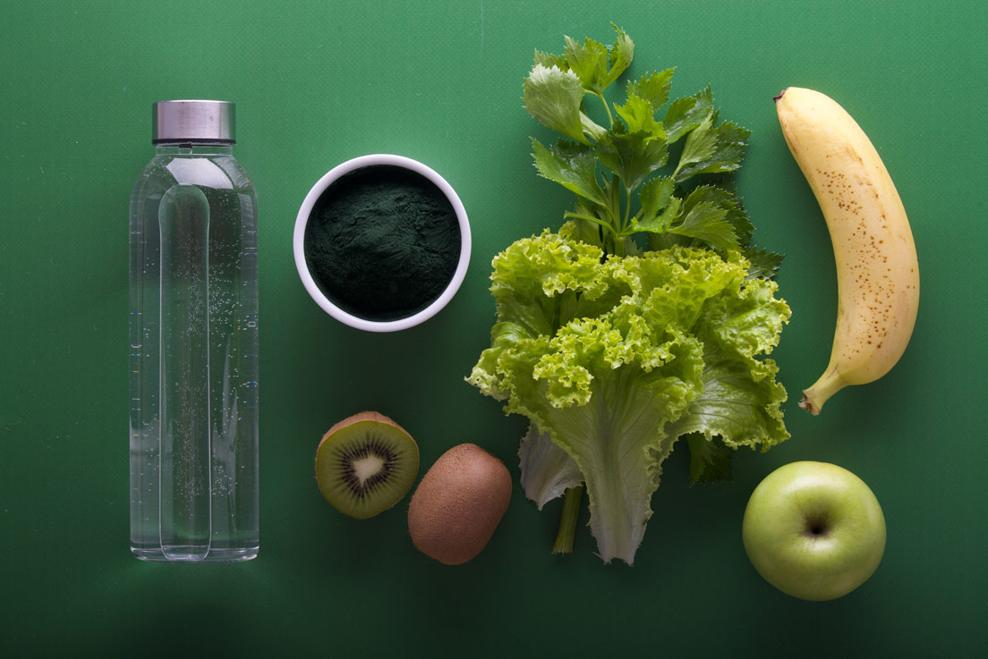 Top view of a bottle, greens and fruits