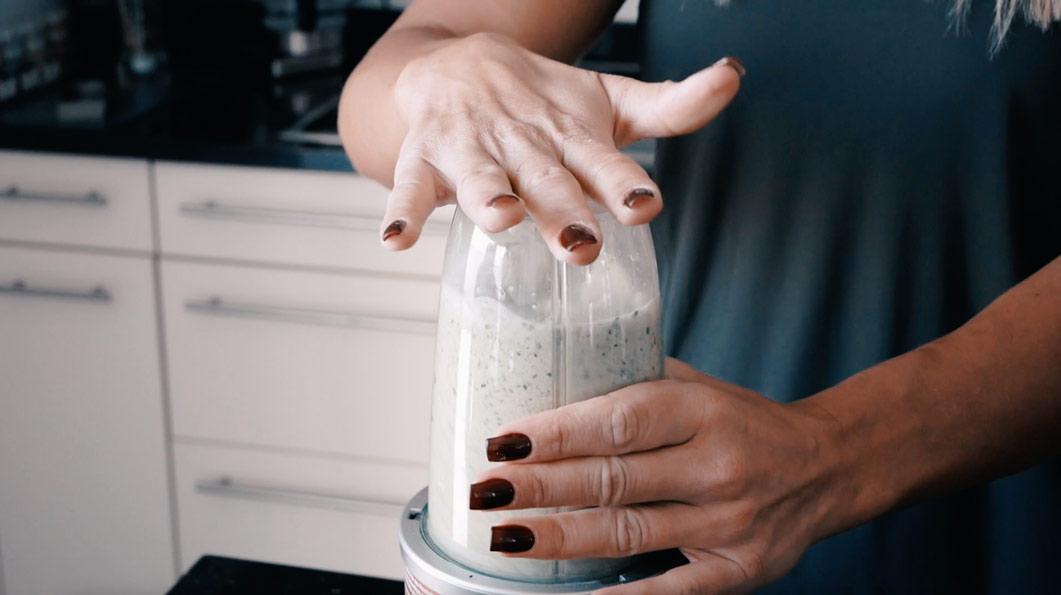A woman prepares a protein shake in a blender
