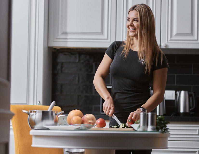 A woman chopping cucumber and smiling