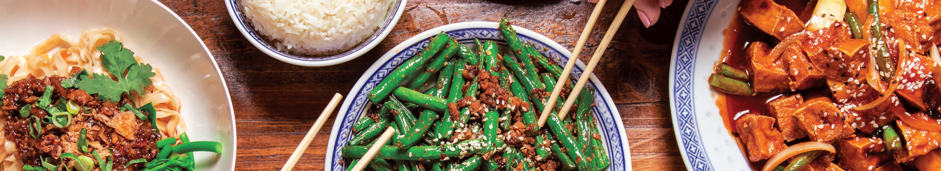 Aerial view of a banquet with green beans, tofu, noodles & rice