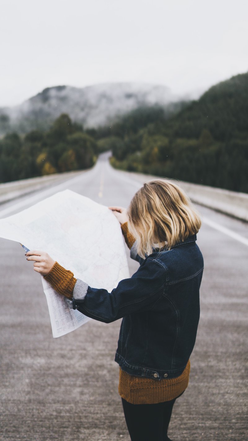 Image of a woman looking at a map in the middle of the road