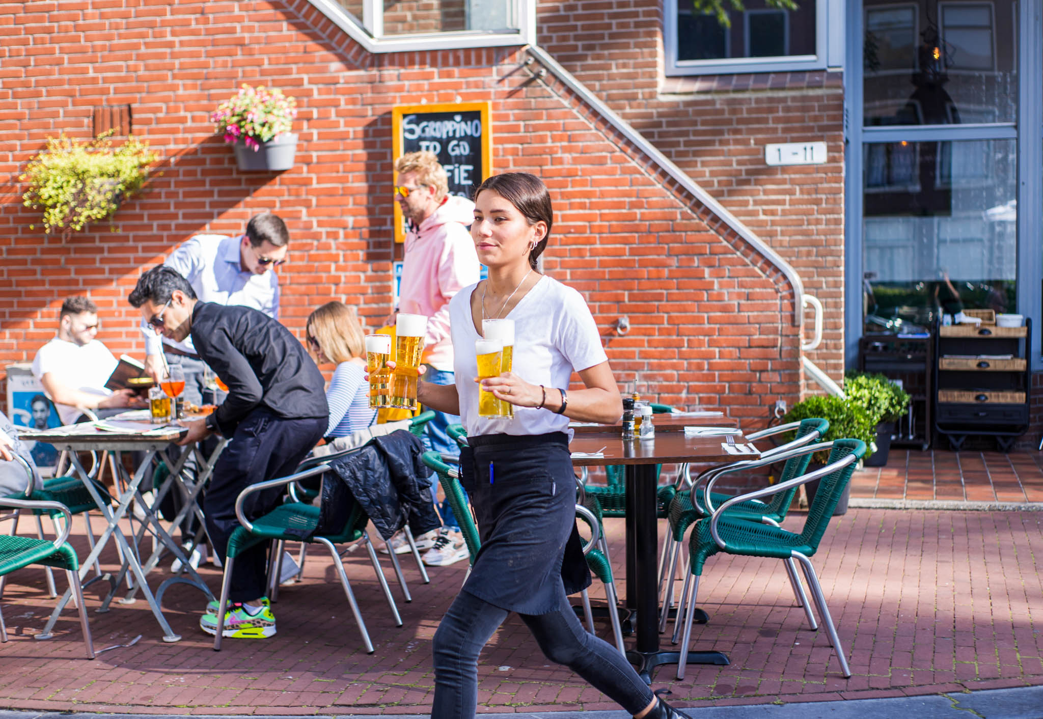 Waitress walking outside a restaurant with beer glasses